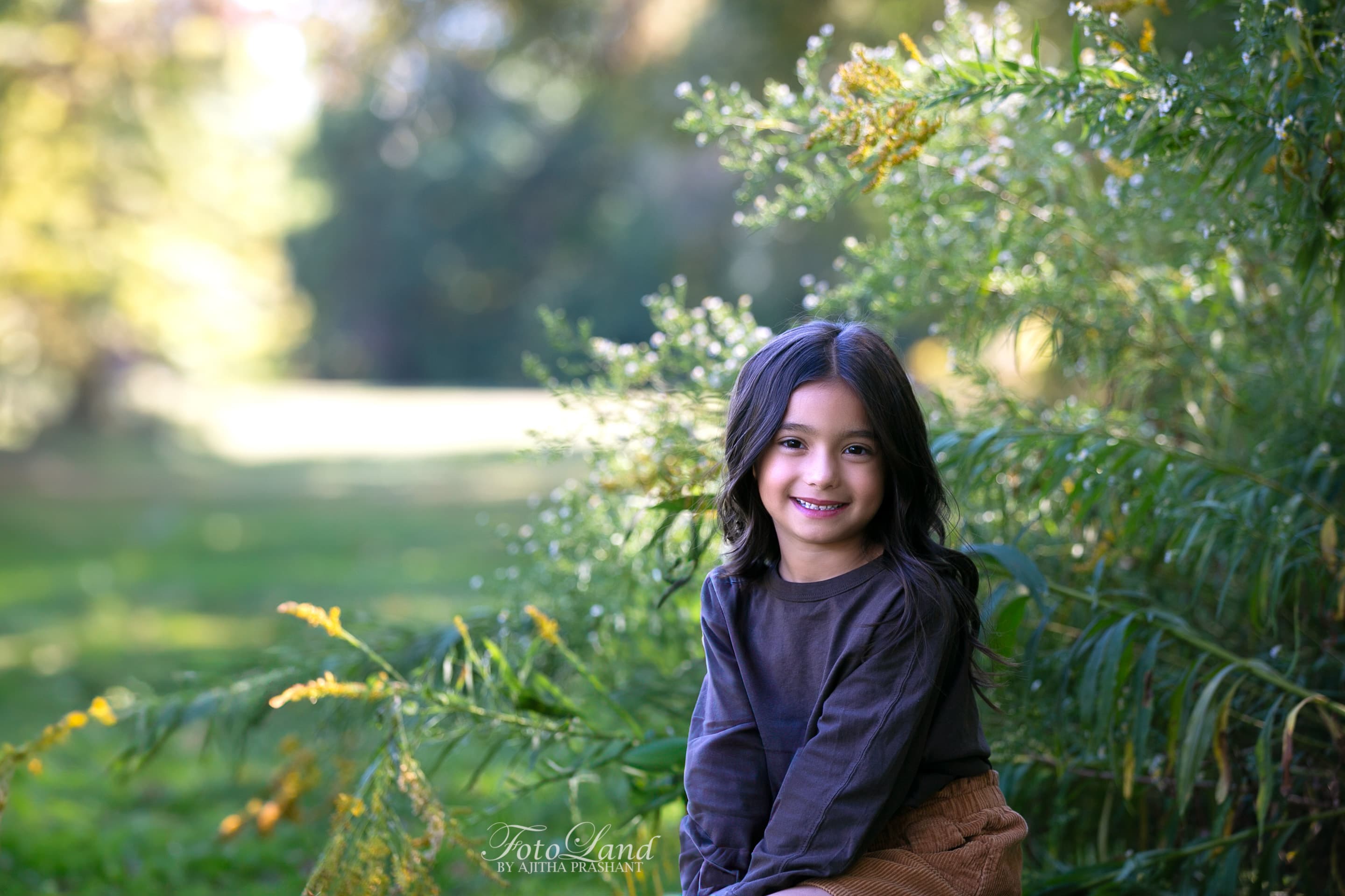 Joyful little girl smiling in a field of wild grass under soft sunlight